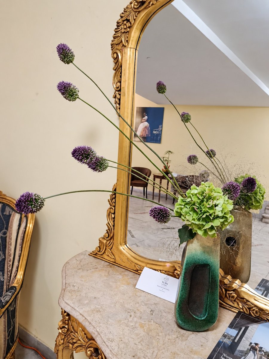 Allium mov și hortensie verde într-un vas de ceramică, lângă o oglindă aurită
